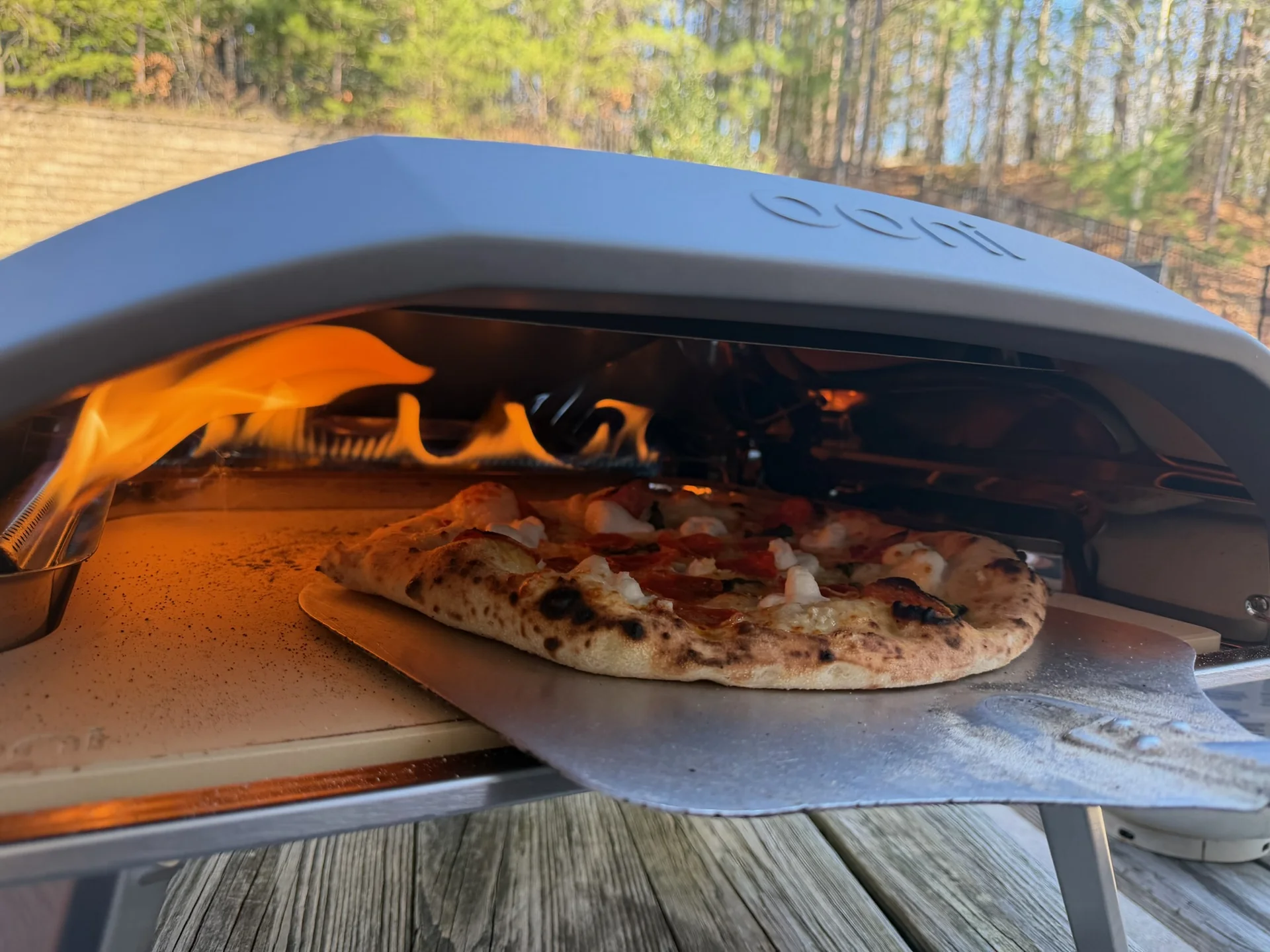 Fresh Italian pizza baking beside flames in the catering oven